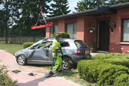 Auto over de kop tegen gebouw