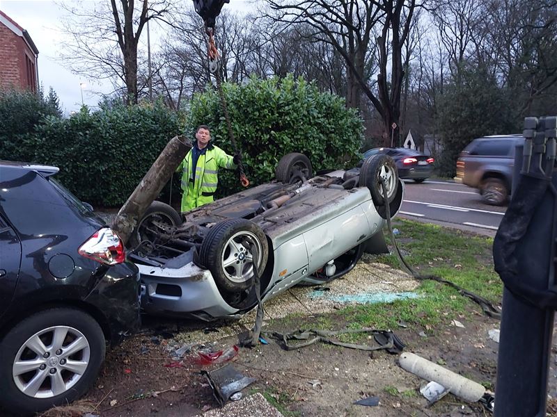 Auto over de kop en sleurt verlichtingspaal mee