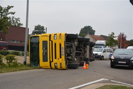 Truck met zand kantelt op rotonde